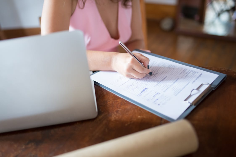 An image of a woman writing something on a document