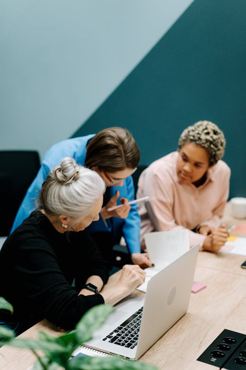 An image of people discussing while looking at a laptop