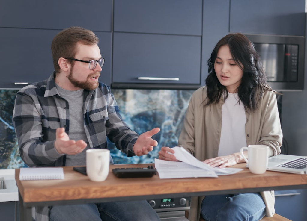 a couple arguing with each other while going through documents on a table
