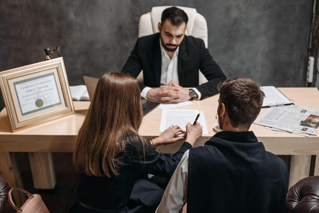 a divorced couple signing a document at a lawyer’s office