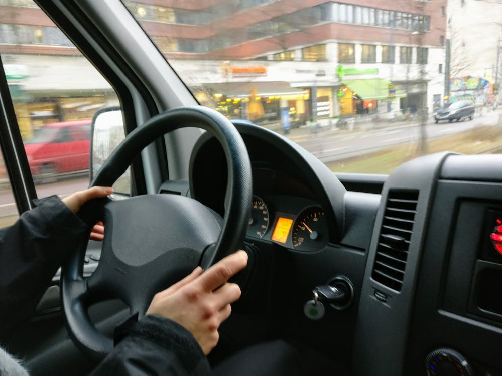 a person holding a steering wheel of a car while driving