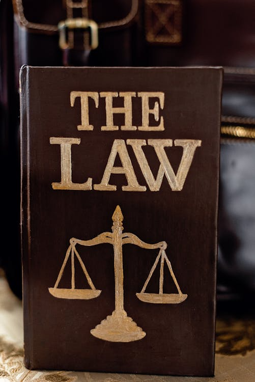 close-up of a law book with a balance scale on it, in front of a black briefcase